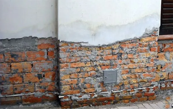 Struttura muraria esterna di un edificio rovinata dalle infiltrazioni di risalita